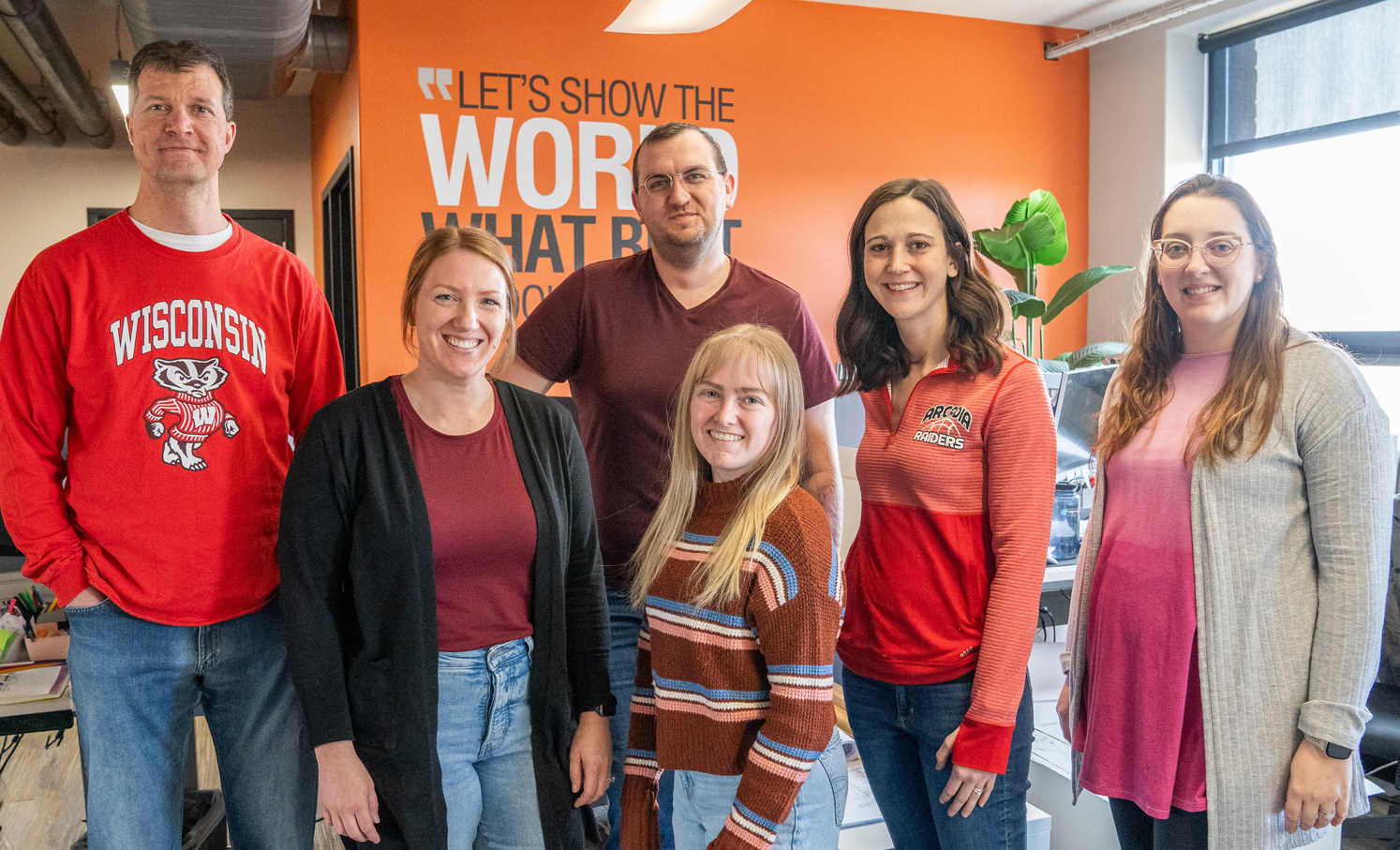A group of 6 people are smiling looking at the camera