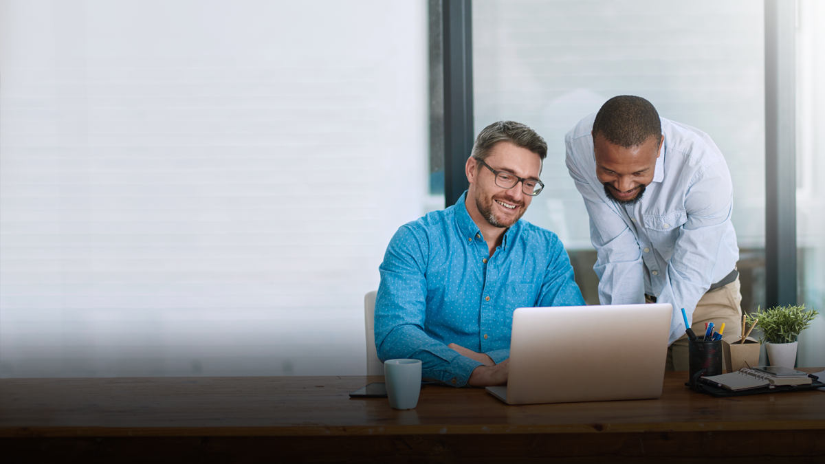 Ashley Furniture team members collaborating in the office looking at a laptop.