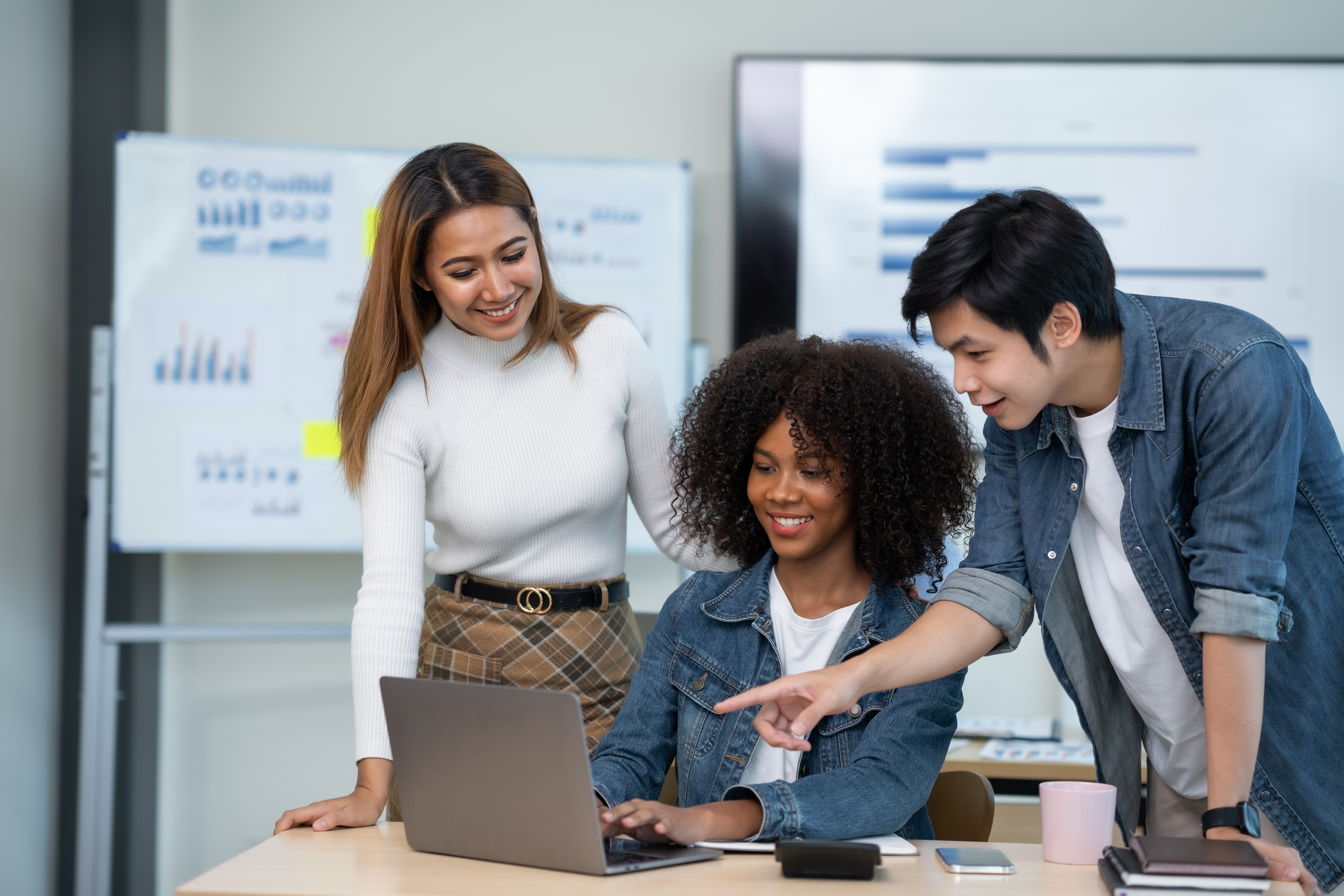 A group of people are huddled together smiling looking at a computer