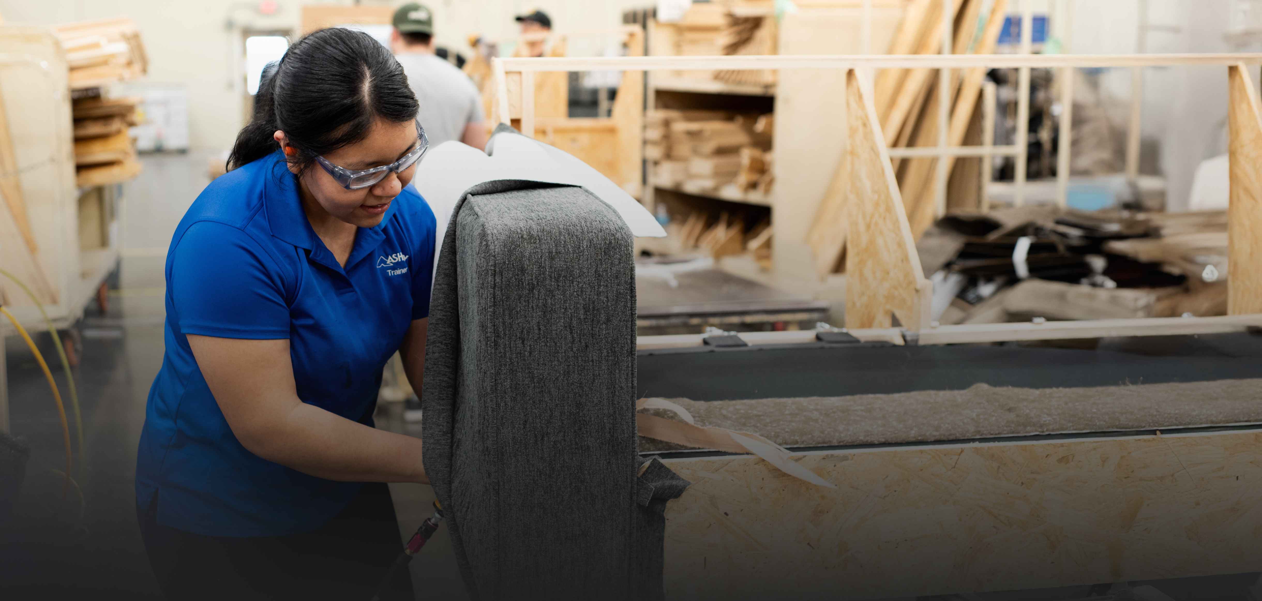 Female Ashley Furniture employee working in manufacturing facility building a couch.