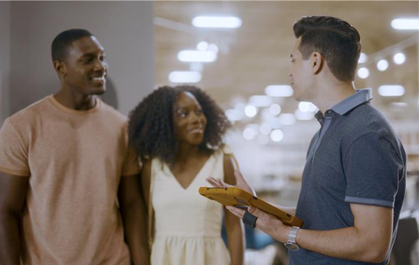 Two customers are shown shopping for furniture, and one sales associate