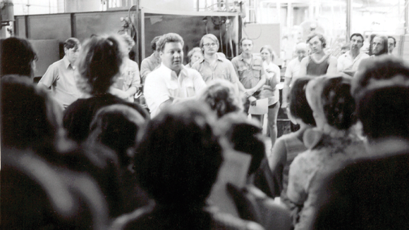 Historic moment of people listening to Todd Wanek in a huddle.