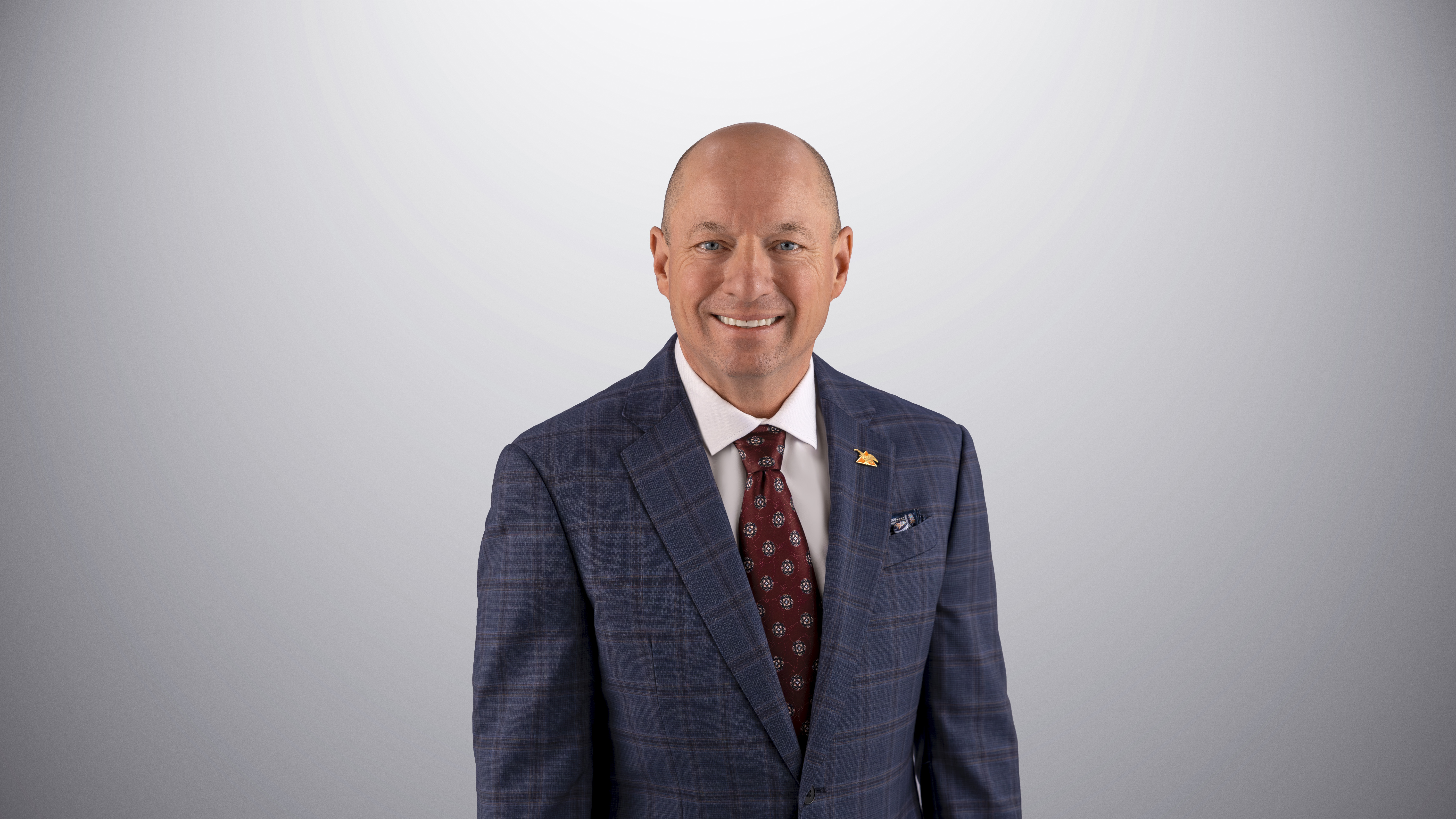 President and CEO of Ashley Furniture smiling in a blue suit at the camera.